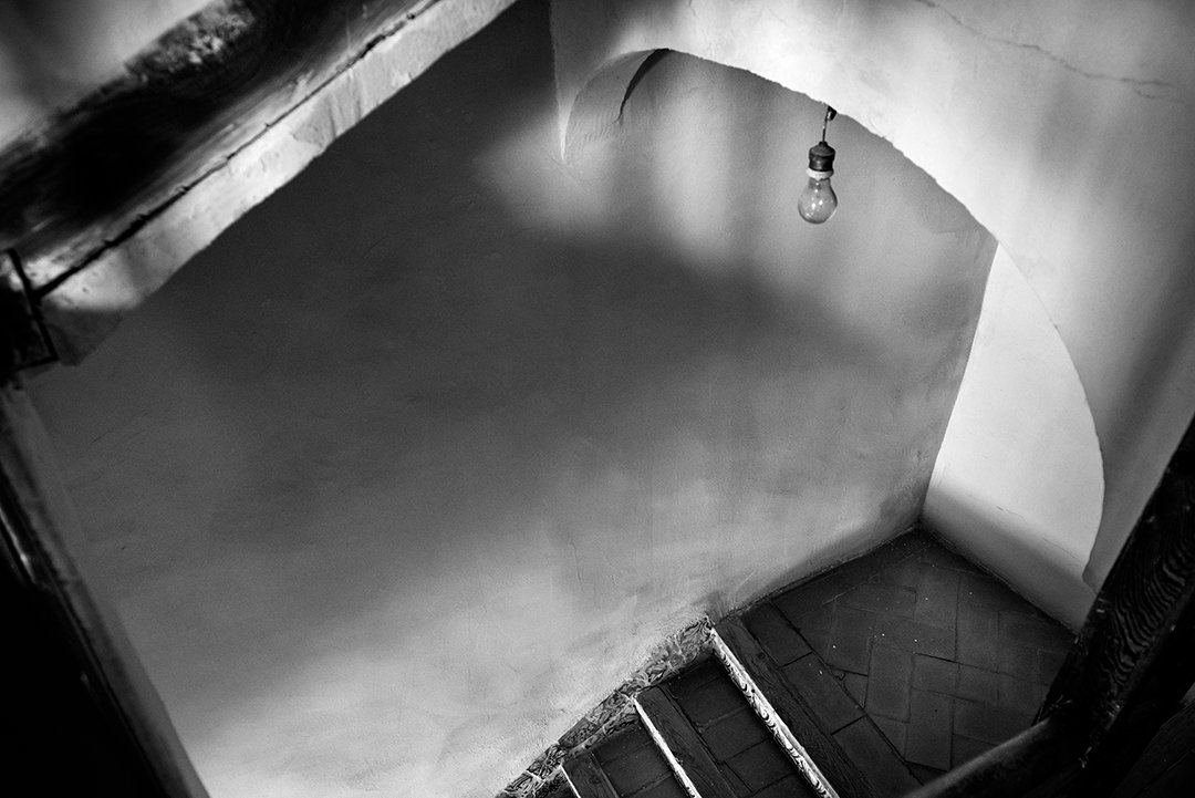 An interior staircase with a light bulb and illuminated walls.